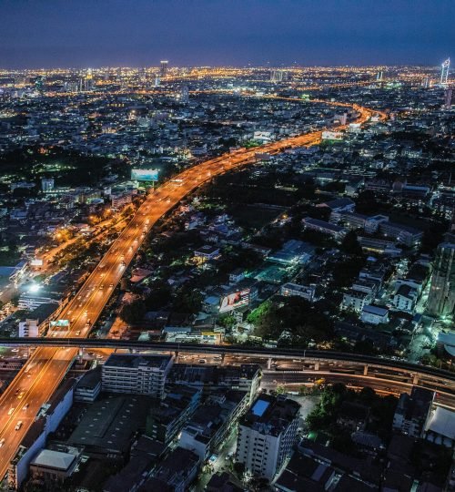 A stunning aerial view of Bangkok at night, showcasing the illuminated skyline and bustling urban life.